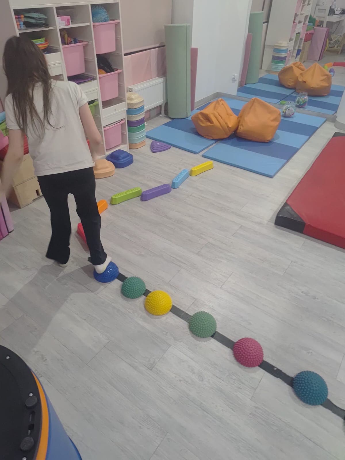 Dziecko przechodzi przez tor równoważny przygotowany w sali terapii.