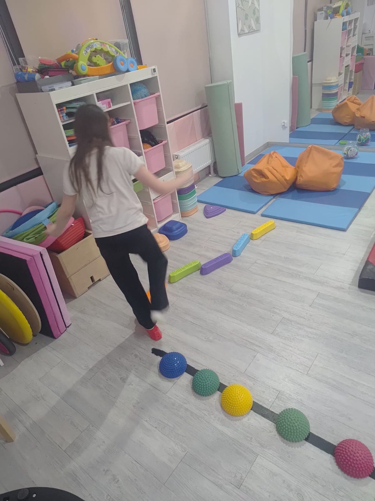 Dziecko przechodzi przez tor równoważny przygotowany w sali terapii.