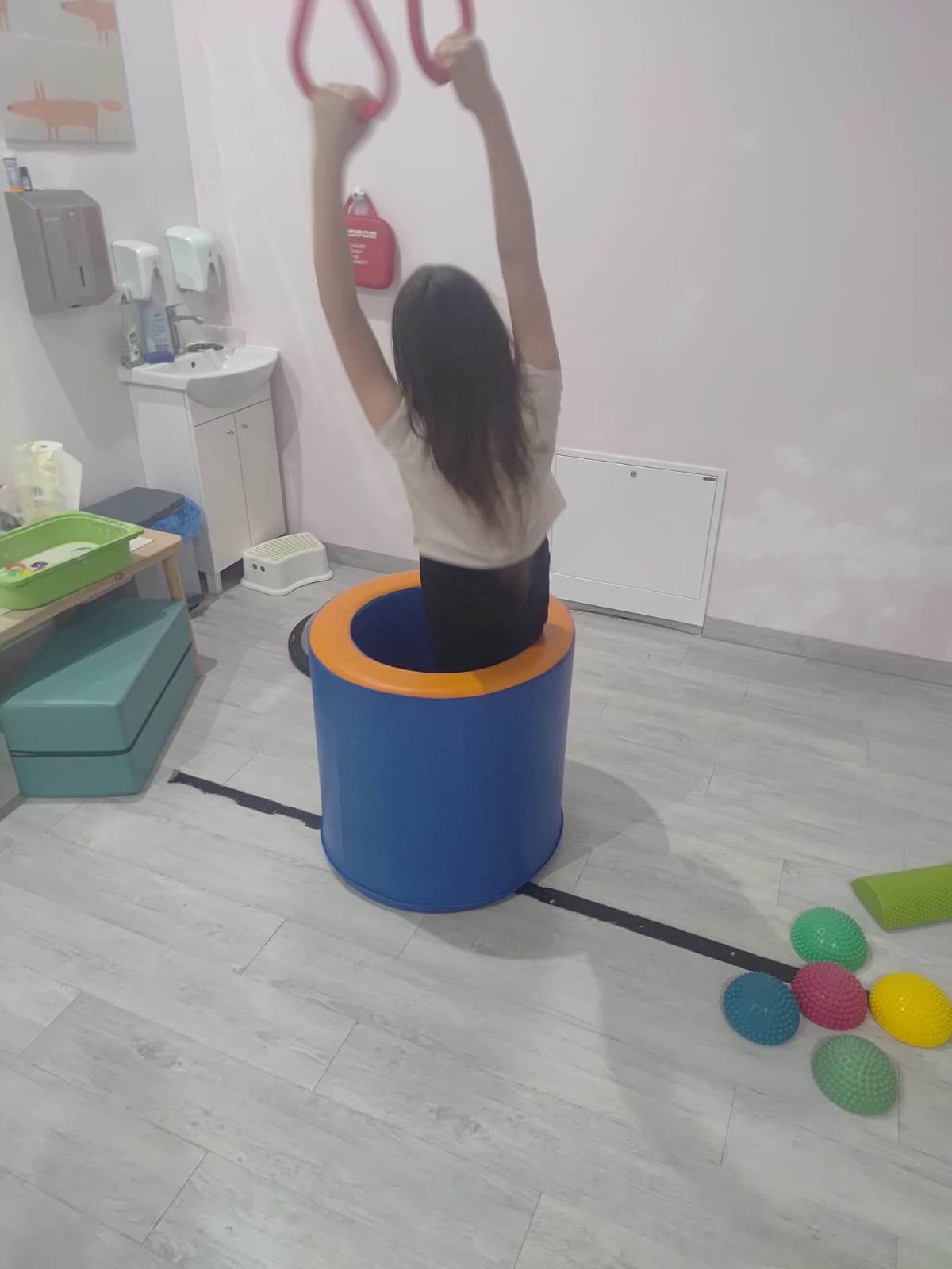 Dziecko przechodzi przez tor równoważny przygotowany w sali terapii.