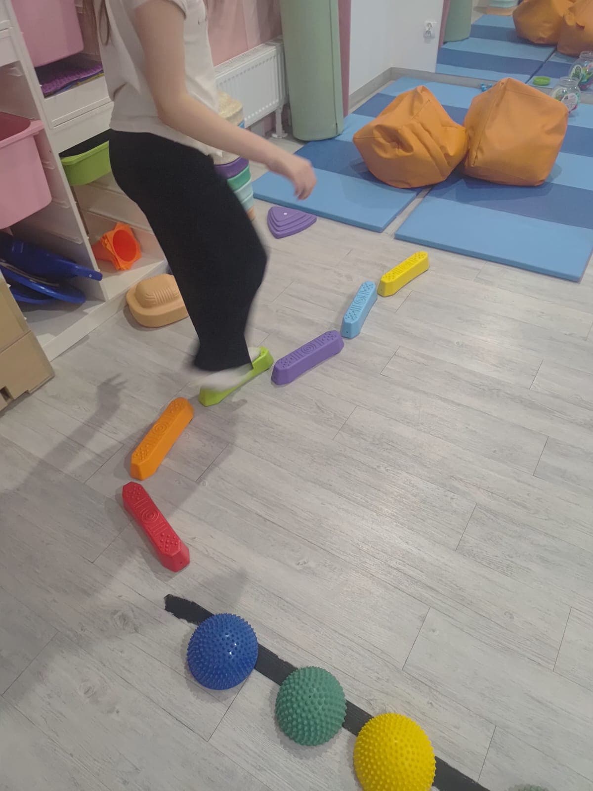 Dziecko przechodzi przez tor równoważny przygotowany w sali terapii.