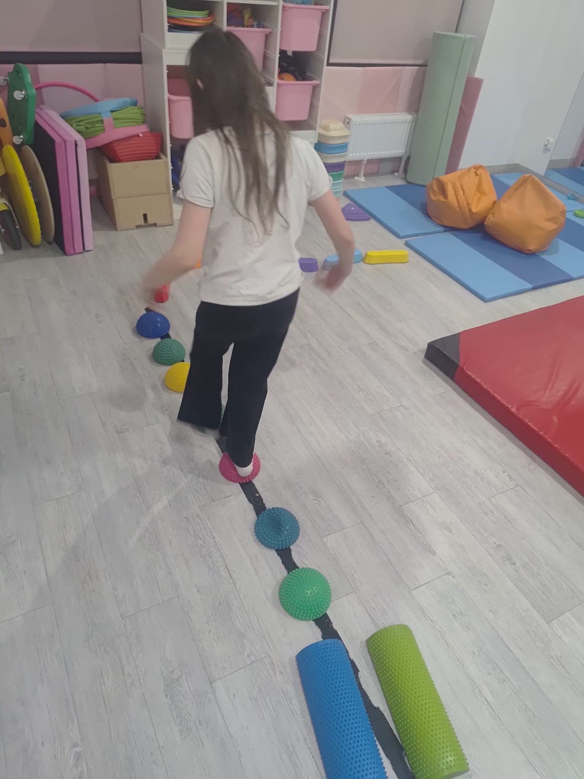 A child moves through a balance path prepared in the therapy room.
