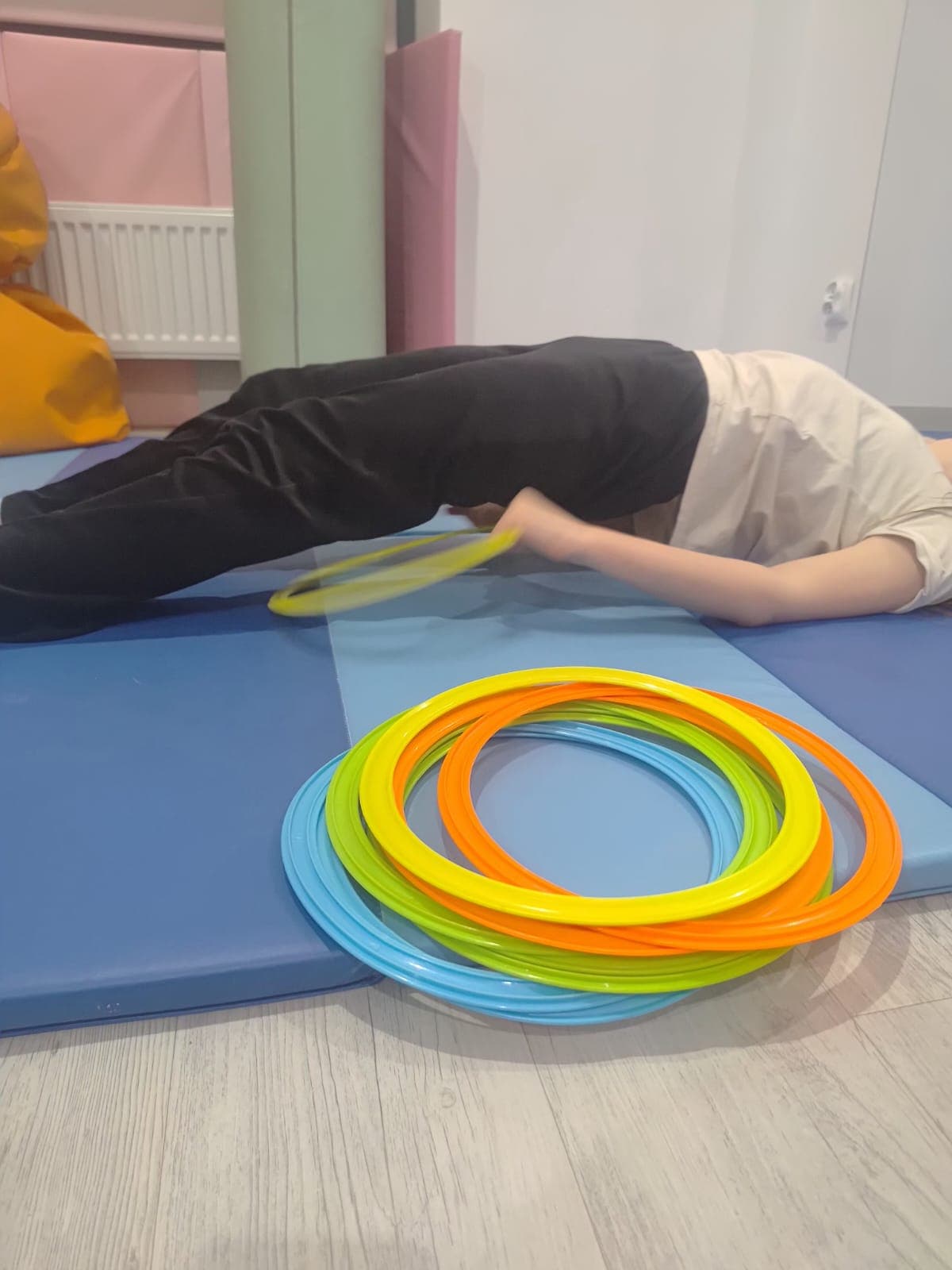 Dziecko wykonuje cwiczenie ruchowe na materacu podczas terapii.