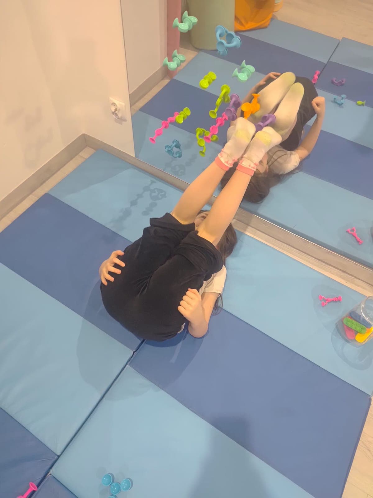 Dziecko wykonuje cwiczenie ruchowe na materacu podczas terapii.