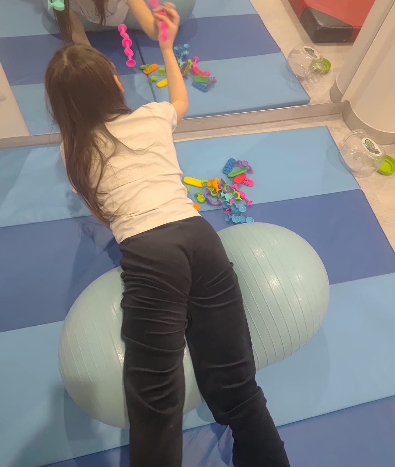 Dziecko wykonuje cwiczenie ruchowe na materacu podczas terapii.