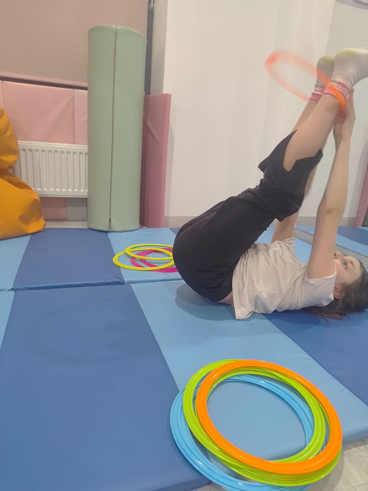 Dziecko wykonuje cwiczenie ruchowe na materacu podczas terapii.