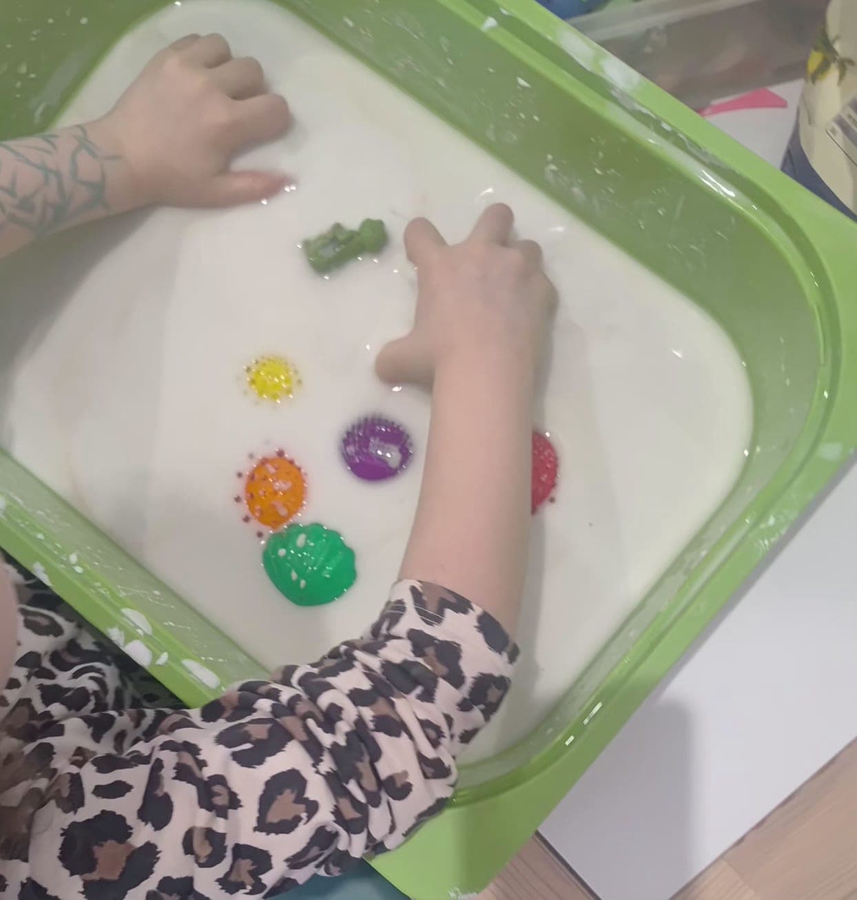 Dziecko wykonuje sensoryczne zadanie manualne przy stoliku.