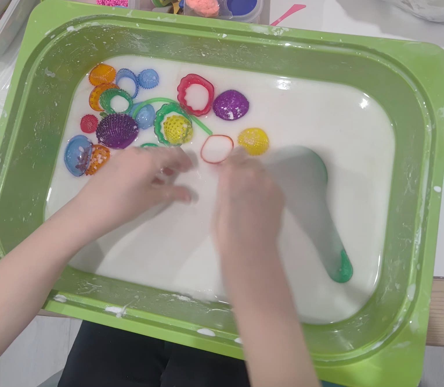 Dziecko wykonuje sensoryczne zadanie manualne przy stoliku.