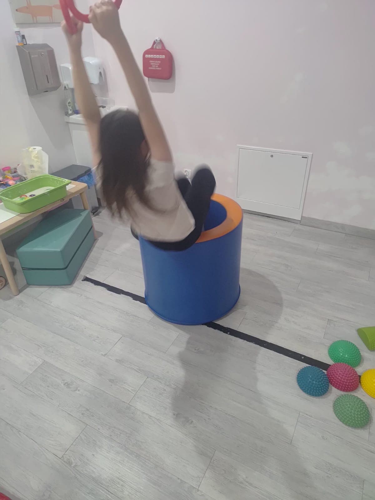 Dziecko wykonuje ćwiczenie równoważne z wykorzystaniem pomocy terapeutycznych.