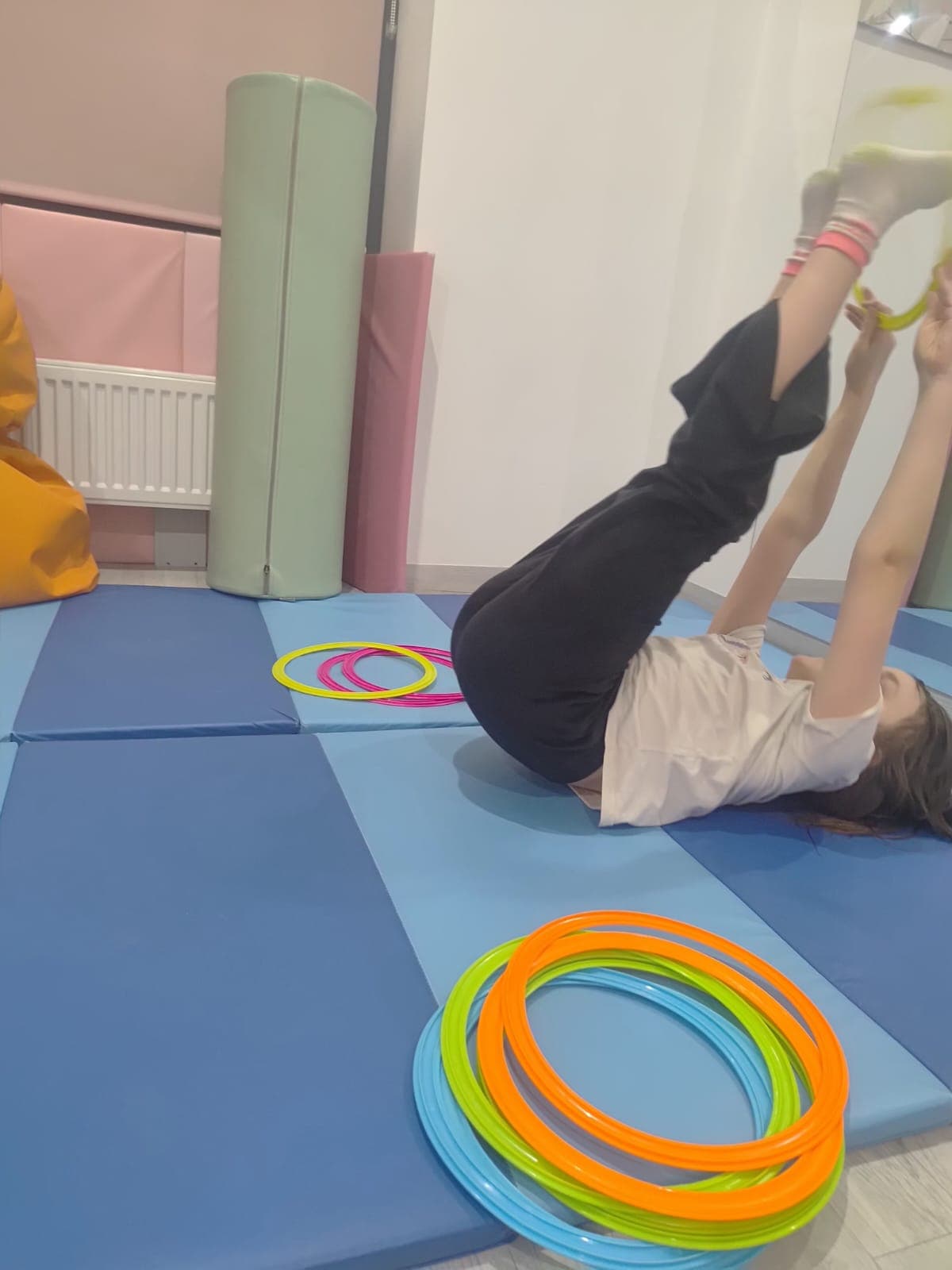 Dziecko wykonuje ćwiczenie równoważne z wykorzystaniem pomocy terapeutycznych.