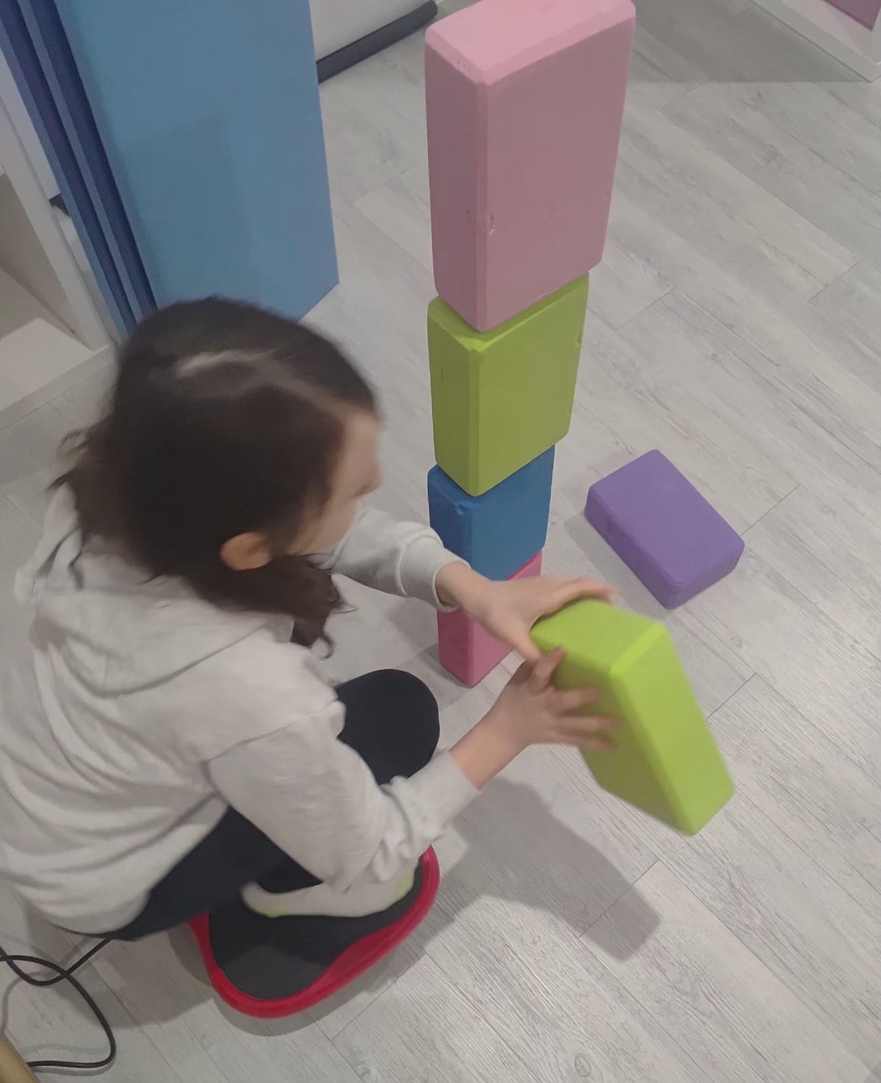 A child performs an exercise on a vibration platform during therapy.